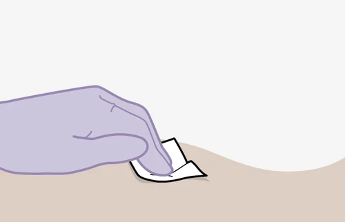A lilac-colored gloved hand applying a small white adhesive bandage to a flesh-colored skin surface