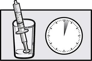 Siringa con liquido all'interno inserita in un bicchiere accanto a un orologio che indica l'ora esatta
