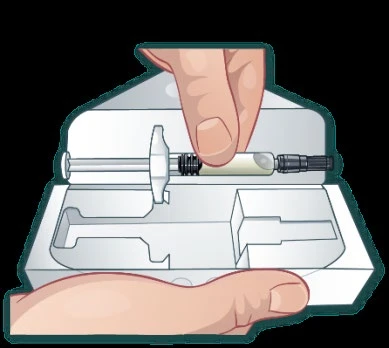 A hand holding a syringe with clear liquid above an open white plastic container for drug packaging