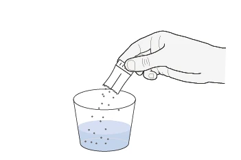 A hand holding an open sachet above a glass containing blue liquid as powder pours into it