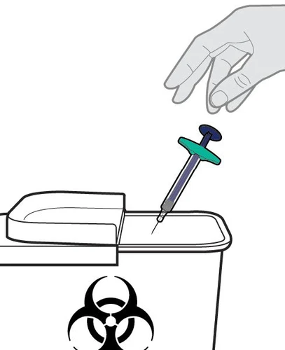 A hand holds a syringe with needle pointing downward to dispose of it into a biohazard waste container with a biological hazard symbol