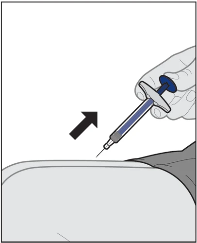 A hand holds a syringe with blue liquid tilting it downward to inject the contents into the upper thigh