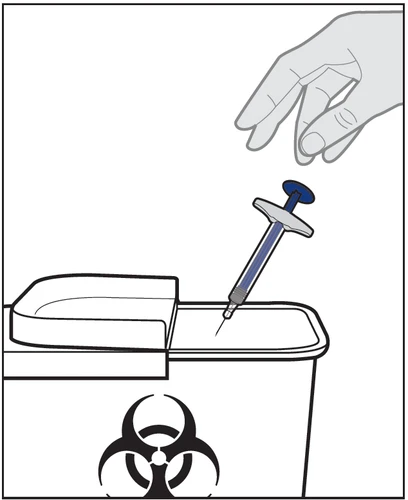 A hand holds a syringe with needle pointing downward for disposal into a biohazard waste container with a biological hazard symbol