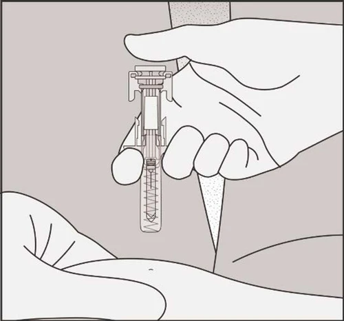 Una mano tiene verticalmente un dispositivo medico a forma di siringa trasparente con una molla interna sopra un braccio disteso