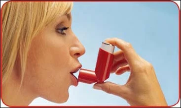 Perfil de una mujer rubia usando un inhalador rojo, sosteniendo el dispositivo en la boca para tomar una dosis del medicamento sobre un fondo claro