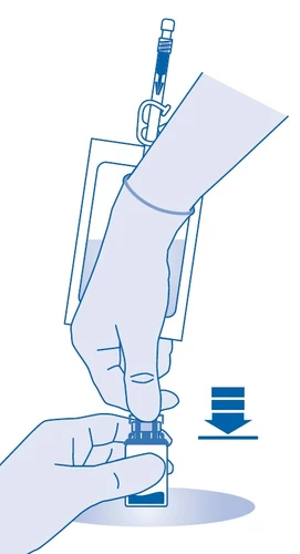 Mano guantata che tiene una fiala, mentre l'altra preme lo stantuffo della siringa verso il basso per aspirare il liquido dal contenitore al fine di preparare il farmaco