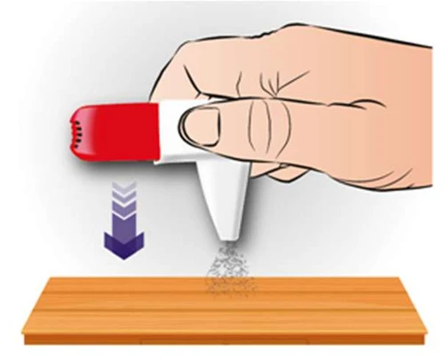 Hand holding a red-and-white inhaler pointing downward over a wooden surface, with fine medication powder being released beneath a purple arrow