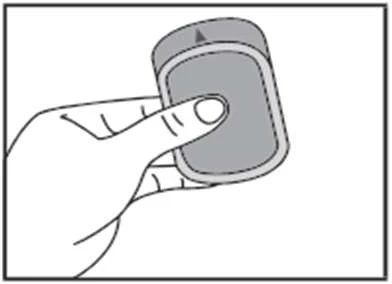 Hand holding with a finger a medical drug delivery device with a rounded shape, showing an arrow indicating the direction of use