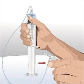 Hands holding a syringe vertically with a thin tube, a red arrow indicating the direction of movement toward the white surface beneath the device