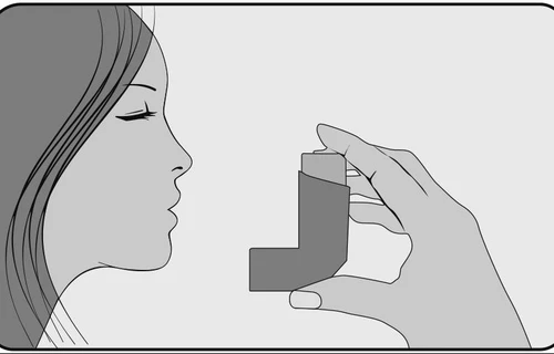 Perfil de una mujer con los ojos cerrados inhalando aerosol de un inhalador en forma de L que sostiene en la mano