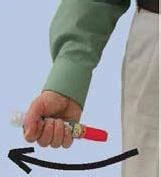 A hand in a green sleeve holding a red injector, with a black arrow indicating the downward movement direction of the device