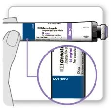 Hand holding a Genotropin medication vial, with a magnified inset showing a close-up of the label marked 12 mg and fields for expiration date and batch number
