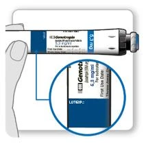 Mano que sostiene el tubo de medicamento Genotropin 5,3 mg/ml con un aumento que muestra la etiqueta con la leyenda LOT y fecha de caducidad del producto