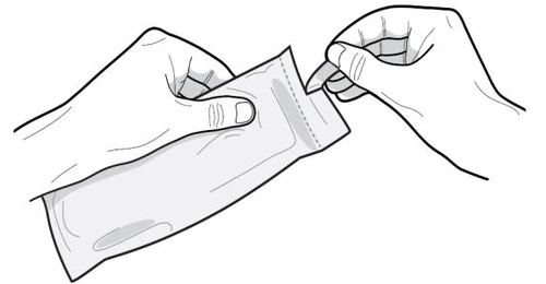 Two hands manually tearing open a perforated paper sachet package containing powder or granular medication