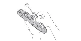 Two hands holding a medical device with an extended needle and a distinctive dosing mechanism ready for drug administration
