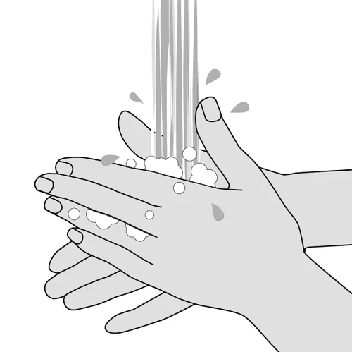 Due mani sotto un getto d'acqua con gocce e schiuma, che illustrano il processo di lavaggio accurato delle mani per mantenere l'igiene