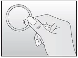 Right hand holding a thin, round ring or medical device between fingers against a light, uniform background