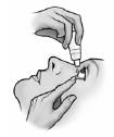 A hand holds a small bottle and applies drops into the eye of a person whose lower eyelid is gently pulled down by the other hand