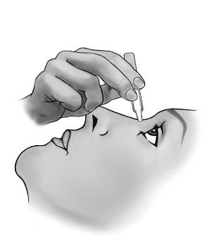A hand holding a small dropper applying drops directly into the eye of a person looking slightly upward, a black-and-white profile face drawing