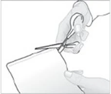 Hand holding scissors cutting the edge of a white package or pouch while the other hand stabilizes the material from below