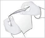 Two hands tearing open a white rectangular pouch or package along the top edge to retrieve the contents