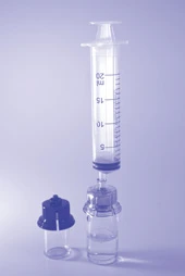 Una jeringa transparente con graduación milimétrica colocada verticalmente sobre un frasco de vidrio con líquido incoloro y tapón oscuro desenroscado, sobre un fondo claro