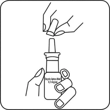 Mano sosteniendo un frasco con la etiqueta Oxyryn Apteo Med 0,5 mg/ml y otra mano desenroscando su tapón blanco para preparar el medicamento