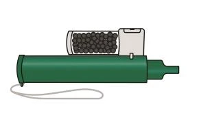 Inhalador verde con depósito transparente lleno de gránulos oscuros, botón blanco y un cordón delgado en la parte inferior
