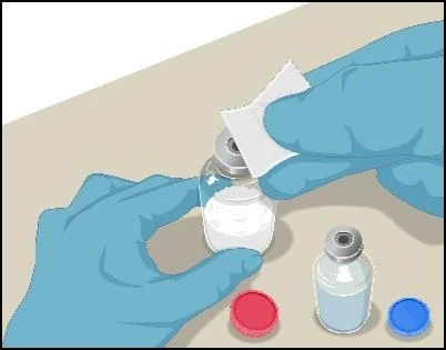 Hands wearing blue medical gloves holding a glass vial containing white powder, with another vial and a red and blue cap placed beside it