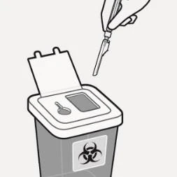 Mano sosteniendo una aguja sobre un contenedor abierto de residuos médicos con el símbolo de biohazard para la eliminación segura de instrumentos