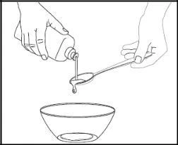 Two hands pouring liquid from a bottle directly into a spoon held above a bowl prepared to receive the medication dose