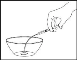 A hand holding a syringe with a long needle, injecting fluid directly into a transparent bowl filled with liquid