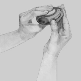 Two hands holding and rotating a round, plastic component of a medical device against a uniform light background