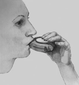 A woman in profile holding a small, round medical device for inhalation or aerosol drug delivery to her mouth