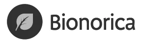 Logo firmy Bionorica przedstawiające jasnoszary kształt liścia umieszczony wewnątrz ciemnego koła obok czarnego napisu Bionorica