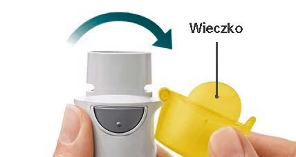 Dłoń zdejmuje żółte wieczko z białego urządzenia medycznego, co wskazuje strzałka skierowana w dół nad górną częścią obudowy