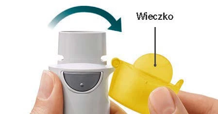 Dłonie zdejmują żółte wieczko z białego urządzenia medycznego, wskazując strzałką kierunek ruchu oraz podpisując element jako wieczko