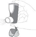 Mano sosteniendo un inhalador de dosis medida, del que se libera una fina neblina del medicamento en forma de aerosol