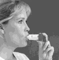 Profil kobiety w czarno-białym ujęciu, która trzyma dłonią przy ustach mały biały inhalator i bierze z niego wdech