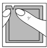 Two hands grasping and peeling off the top layer of a gray packaging or protective cover from a rectangular object with distinct edges