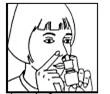 A woman administering a nasal spray into her nose, holding the bottle in one hand and supporting her nose with the other, head slightly tilted backward