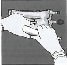 Two hands holding a medical device with an arrow indicating the direction of piston movement for substance delivery