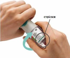 Ręce trzymające fiolkę z lekiem, jedna ręka obracająca nakrętkę, na fiolce widoczne strzałki wskazujące kierunek obrotu