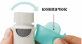 Ręka trzymająca inhalator z otwartą osłonką, wskazaną strzałką i oznaczoną jako osłonka, przygotowanie do użytku